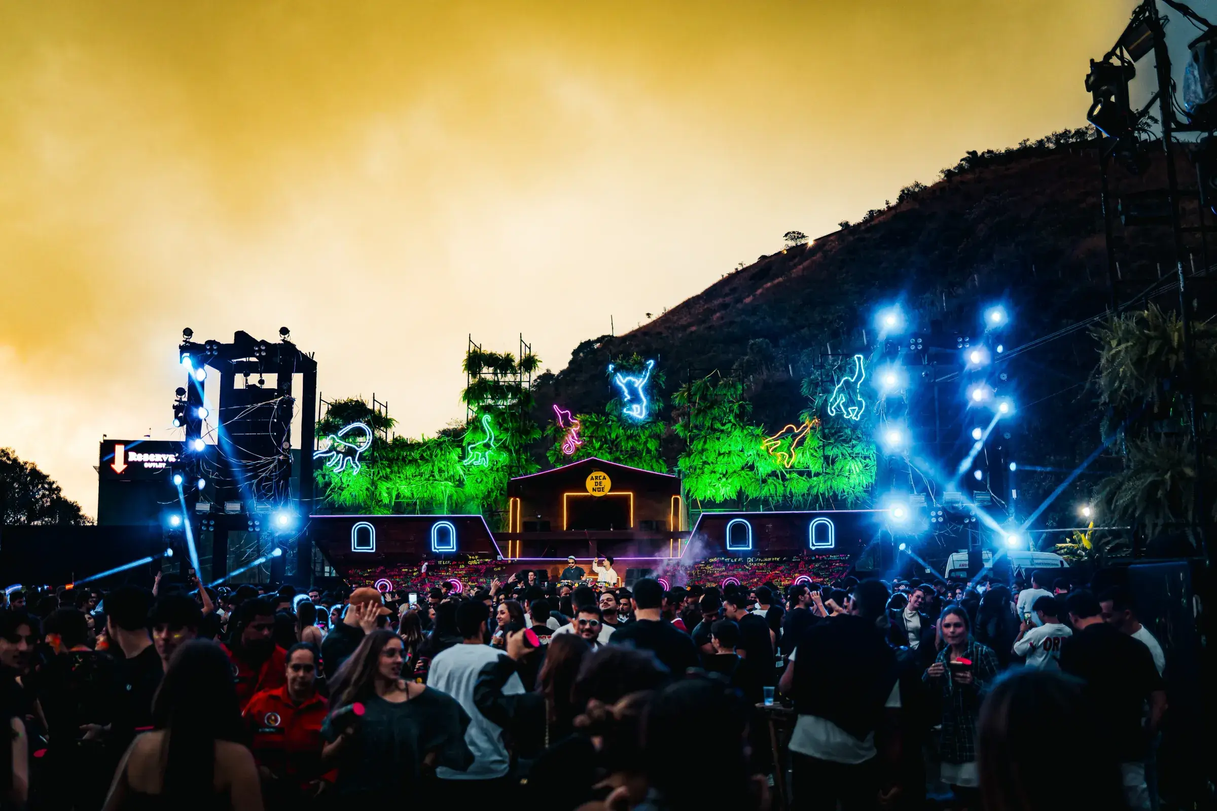 Público em uma festa ao entardecer, de frente para um palco iluminado em Belo Horizonte