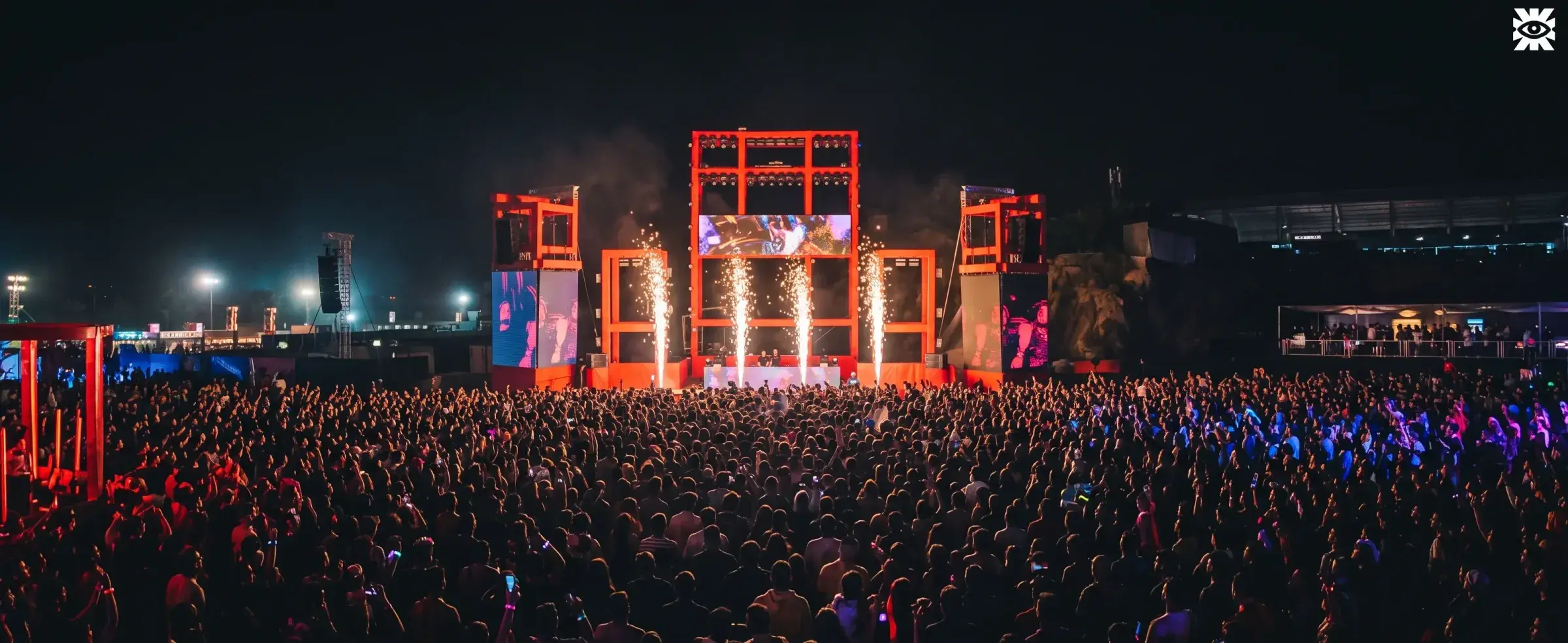 Multidão lotando uma festa à noite, de frente para um palco iluminado em Belo Horizonte